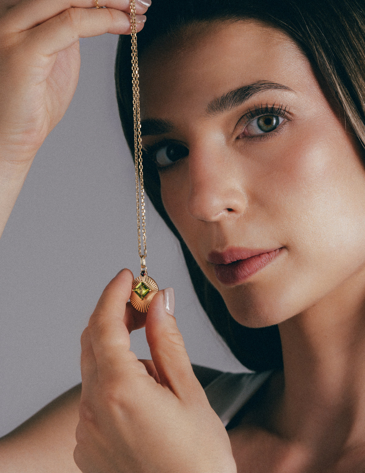 Model holding VERAE peridot and garnet necklace